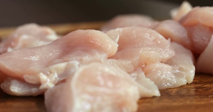  Close up the human hand cutting raw chicken meat on wooden chop board in kitchen room , 4K Dci resolution