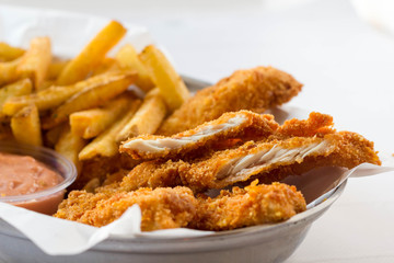 Breaded chicken breast, french fries and tomato dip served in a fast food restaurant.