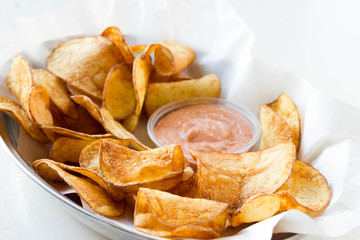 Potato chips with tomato dip served in a fast food restaurant.
