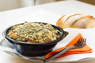 Salad with seeds on top served with freshly baked ciabatta in a plastic bowl.