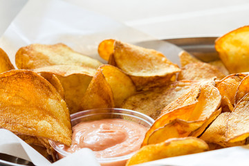 Closeup of fresh, crispy potato chips with tomato dip