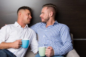 Two attractive guys are drinking coffee. 