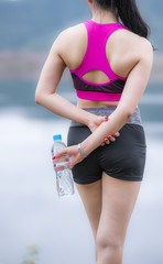 Rear view of a healthy teenager girl holding a mineral water bottle