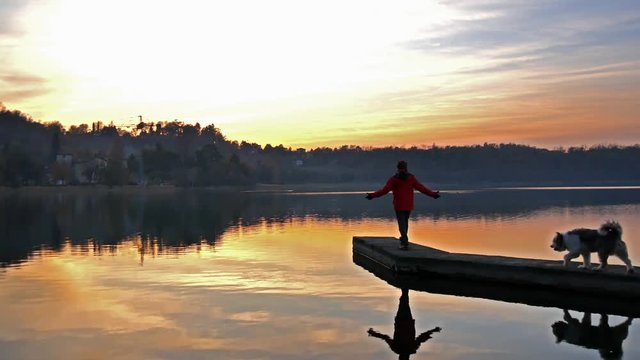 Uomo osserva le luci e i colori del tramonto sulle acque del lago