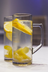 Two high transparent glass cups filled with hot lemon and ginger drink prepared for healing sore throat