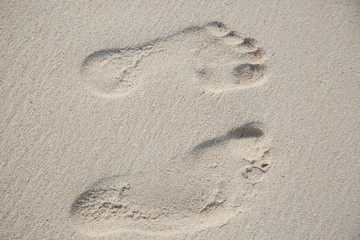 Fototapeta na wymiar Gemeinsam durch das Leben gehen. Zwei unterschiedliche Fussabdruecke im feinen Sand.