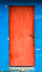 Red door on stained blue wall