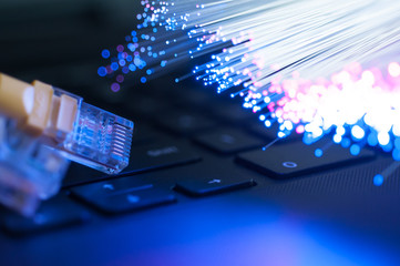Yellow internet connection cable  on laptop ,defocused optical fibre background.