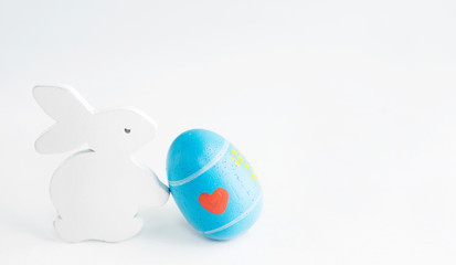Bright Easter background: white wooden bunny with paited egg. Holiday concept. Text space