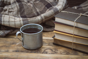 Fototapeta na wymiar Ancient Metal Cup, Warm Plaid, A Pile of Books Tied with a Rope on a Wooden Table