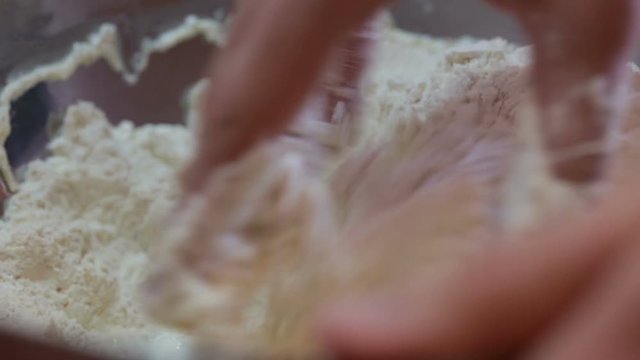 Mani di un uomo che impastano la farina con acqua per fare la pizza italiana tipica in casa.