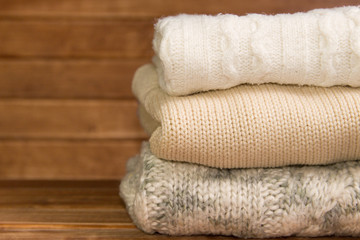 Fototapeta na wymiar Stack of cozy knitted warm sweater ,wooden background