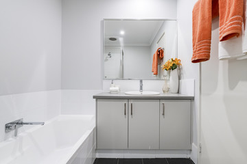 Small modern bathroom interior with white tiling and colourful towels.