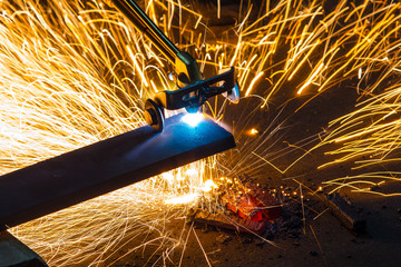 Factory worker cutting metal using acetylene torch, manual plasma cuting in a steel factory lot's...