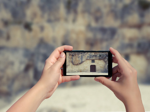 Female taking picture of old stone house in Matera in Italy on mobile phone. (sassi di Matera)