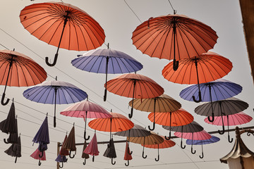 Colorful umbrellas hanging against the sky, decorating city streets.