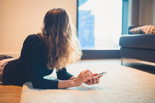 Young woman on floor in apartment with phone
