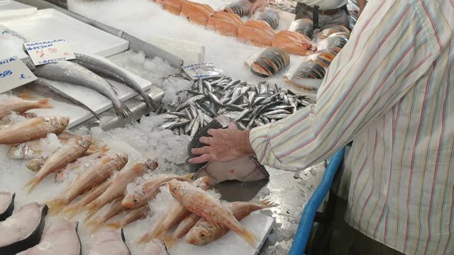 a fishmonger cuts up a fish into cutlets at athens central market in greece