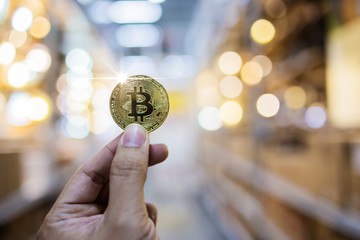 hand hold bitcoin money symbol with blur background of department store business ideas concept