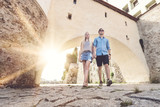 Junges Paar geht durch alten Torbogen mit der Sonne im Rücken