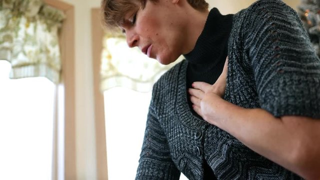 Woman rubbing her sore chest after heart condition ALT