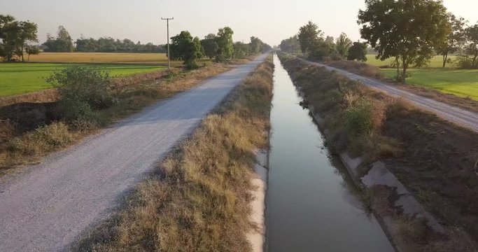 Aerial view from drone flight Irrigation canal, beside two paddy fields rural scene Thailand. Morning sunrise time