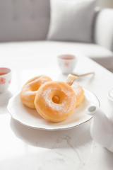 Classic donut. Morning breakfast with tea on table in living room at home.