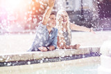 Junges Urlauberpaar hat Spaß an einem Brunnen in der Stadt