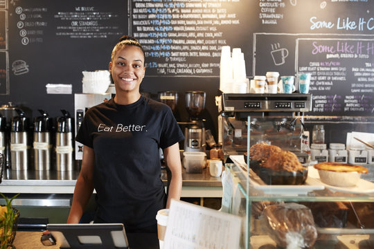 Portrait Of Female Barista Behind Counter In Coffee Shop