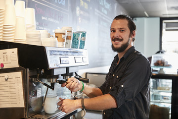 Fototapeta na wymiar Portrait Of Male Barista Behind Counter In Coffee Shop