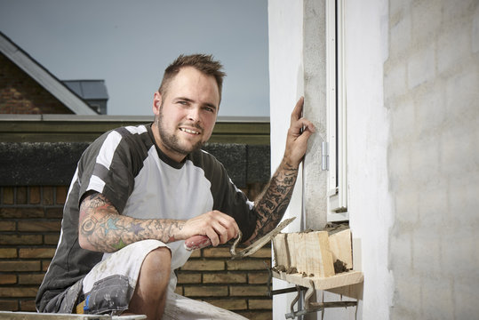 Bricklayer and his bricklayer&acute;s assistant working at a house