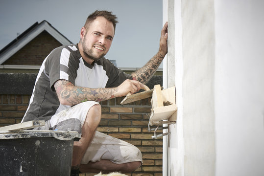 Bricklayer and his bricklayer&acute;s assistant working at a house
