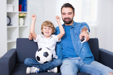 happy young father and son watching football