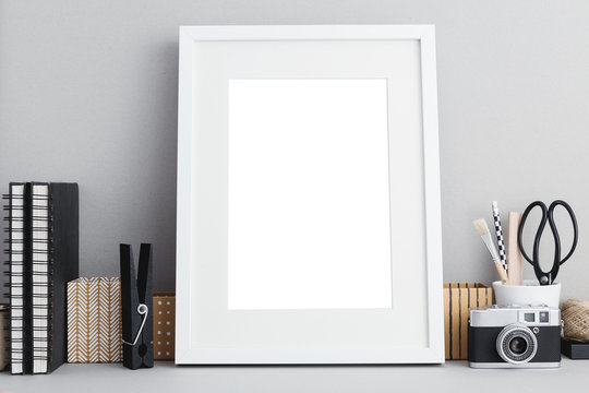 White frame mock up on a desk with books and stationery.