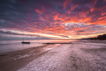 Winter landscape with colorful sunrise at the beach in Gdansk in Poland. Baltic Sea.