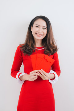 Vietnamese woman traditional festival costume Ao Dai, holding red money pockets.