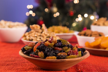 Raisins into a bowl on rustic old wooden table with christmas background.