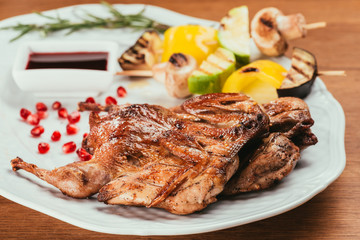 Close-up view of grilled vegetables on plate with fried chicken on wooden table