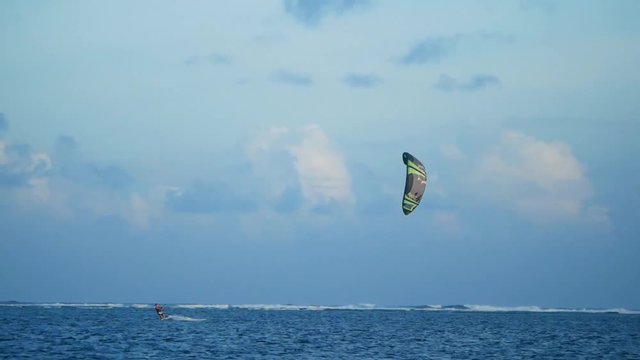 Telephoto lens shot of kitesurfer riding in lagoon in tropical island