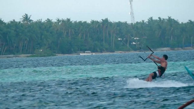 Telephoto lens shot of kitesurfer riding in lagoon in tropical island