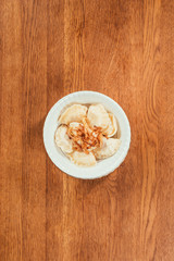 dumplings with fried onions on top laying in plate over wooden surface