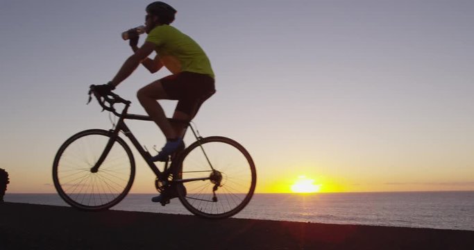 Athlete cyclist man drinking water after intensive cycling biking training, Healthy active lifestyle sports fitness man exercising at sunset. SLOW MOTION RED EPIC.