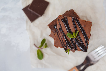 Pieces of healthy vegan pumpkin chocolate brownie with chocolate (carob) syrup on slate board, top...