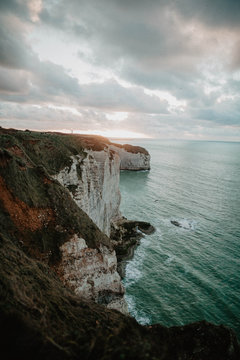 View of cliff by sea against cloudy sky