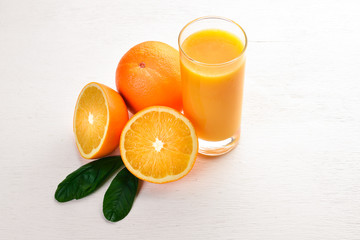 Orange fresh juice and oranges on a wooden surface. Top view. Free space for text.