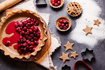 Process of cooking cherry pie on black slate background from above