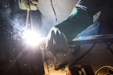 A man welds a metal with a welding machine