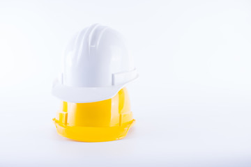 Fototapeta premium White and yellow safety helmet on white background. Hard hat and thick gloves on white isolated background. Safety equipment concept. Worker and Industrial theme.