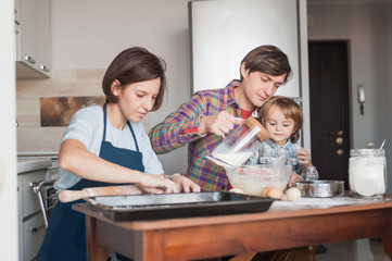 beautiful young family preparing dough for homemade cookies