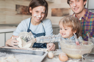 adorable little kid helping his parents with cooking at kitchen